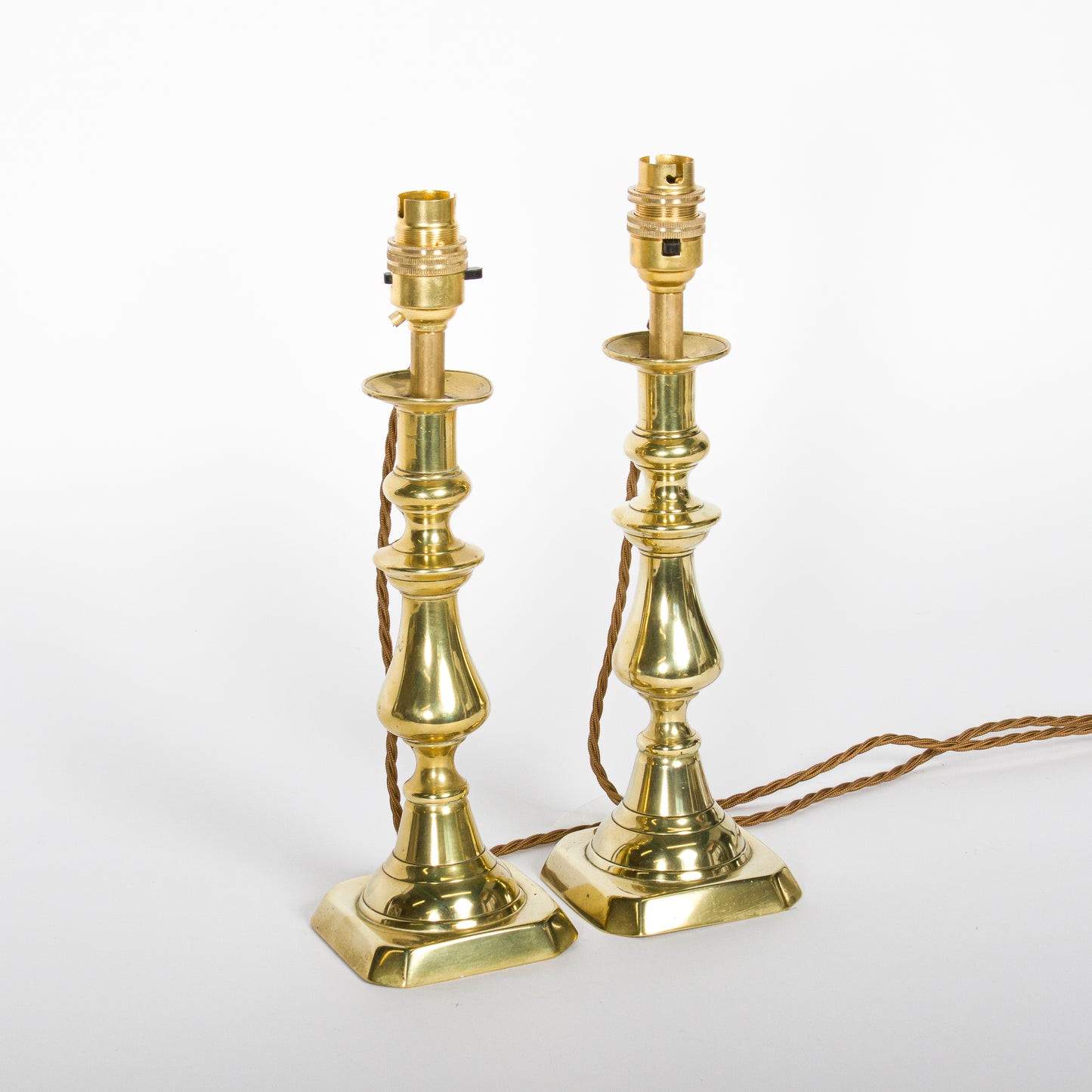 A pair of brass candlesticks converted to lamps, circa 1850